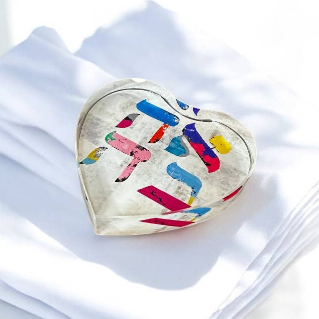 Heart-shaped decorative item with colorful patterns on a white surface
