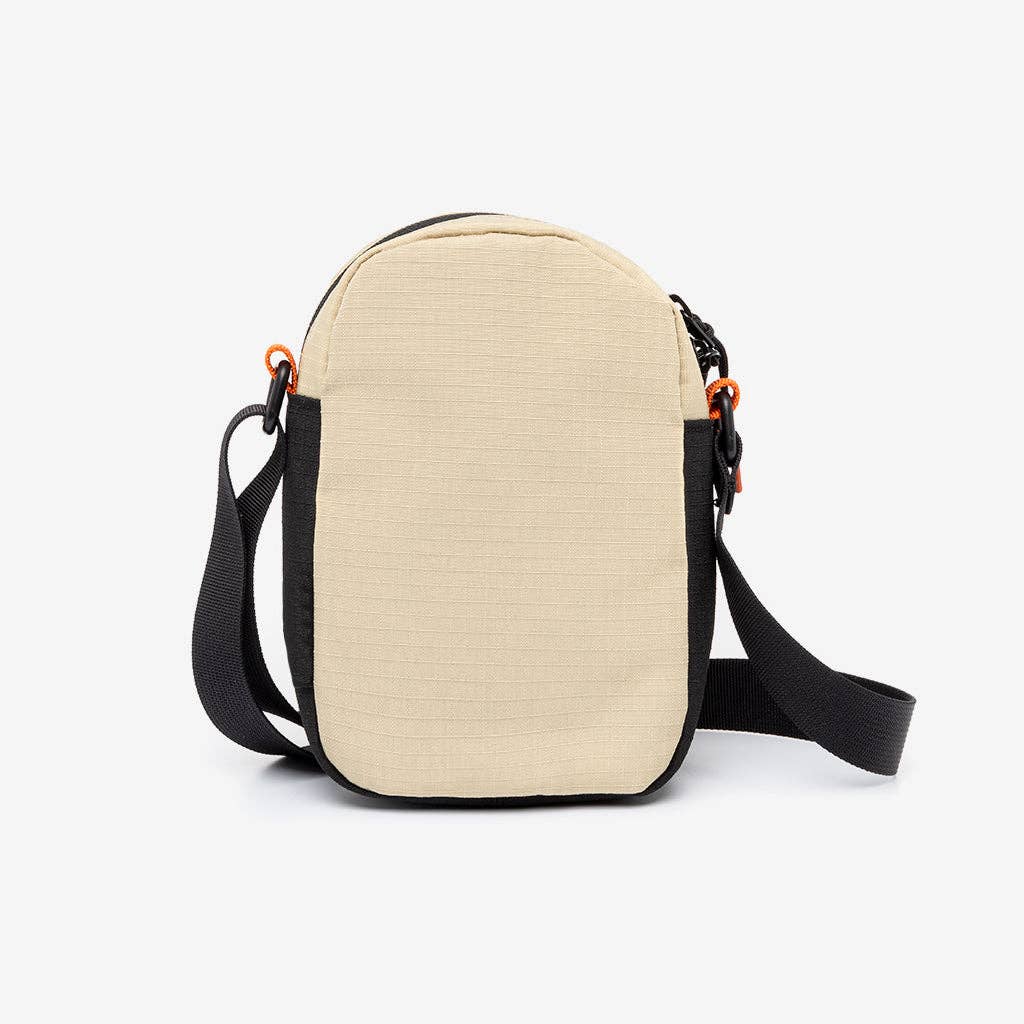 Beige crossbody bag with black straps on a white background