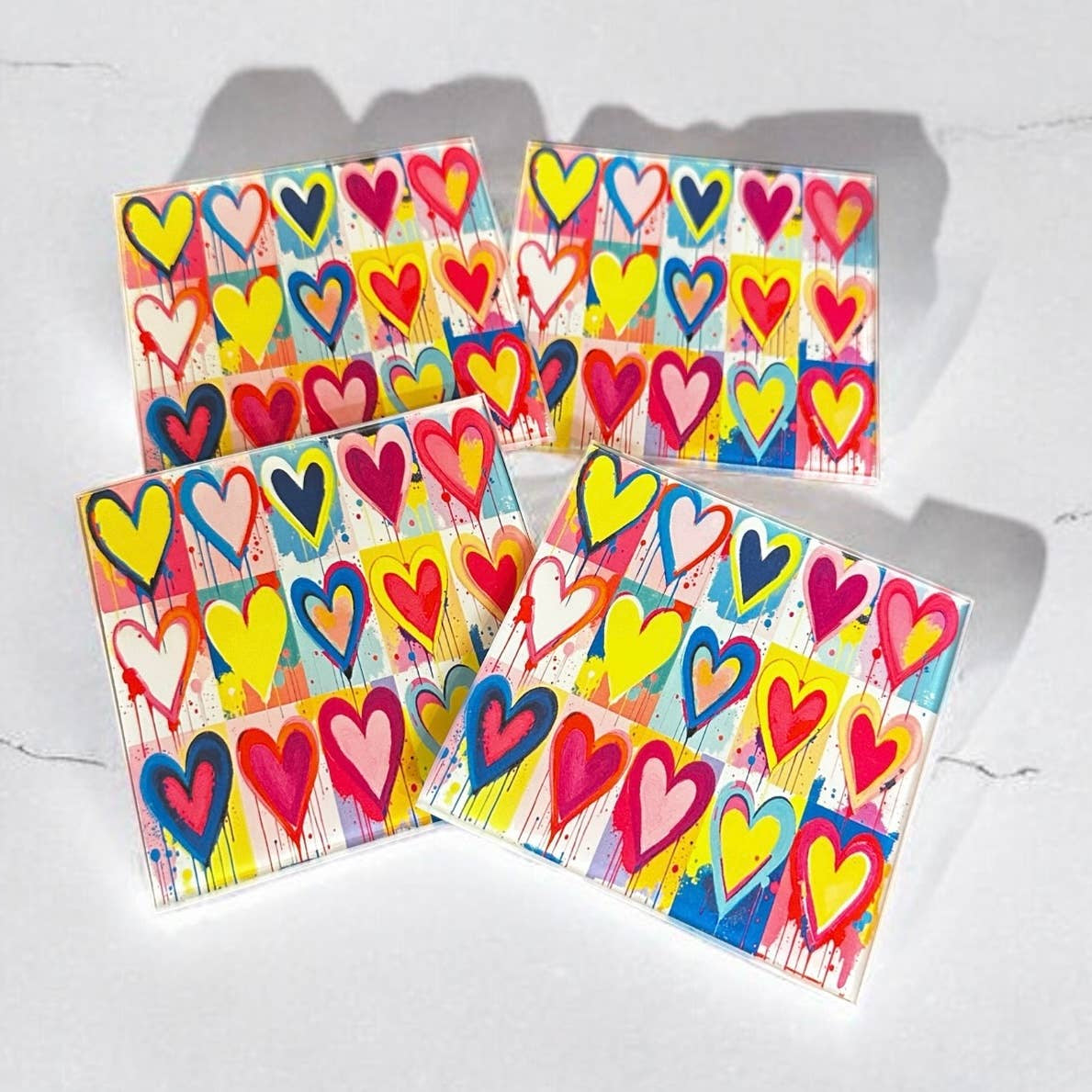 Four colorful greeting cards with heart designs on a white surface