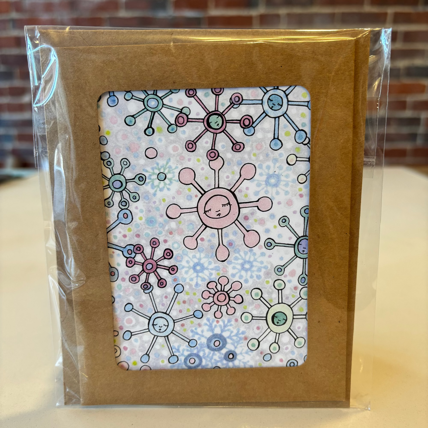 Packaged product with a colorful design on a clear plastic cover against a brick wall background