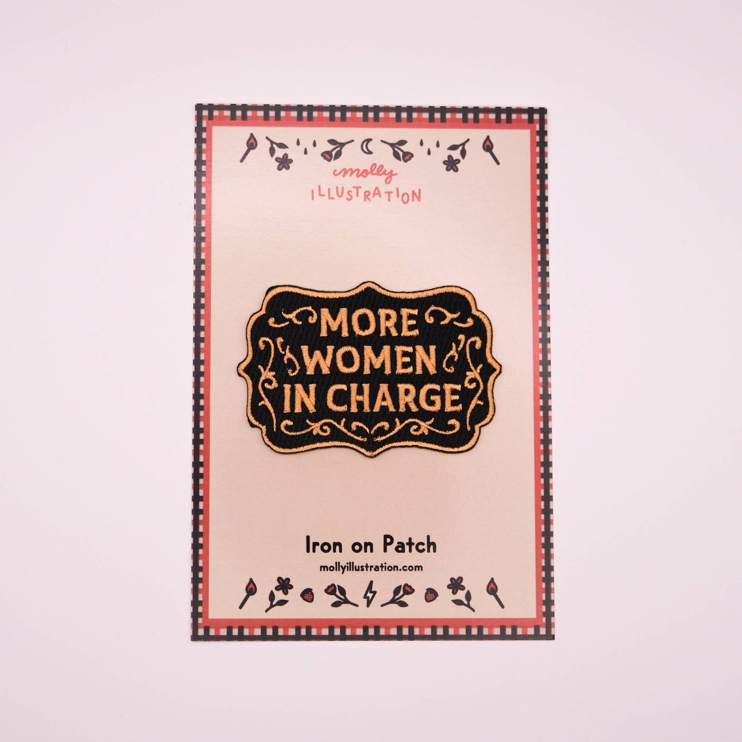 Iron on patch with 'More Women in Charge' text and decorative border on a light pink background