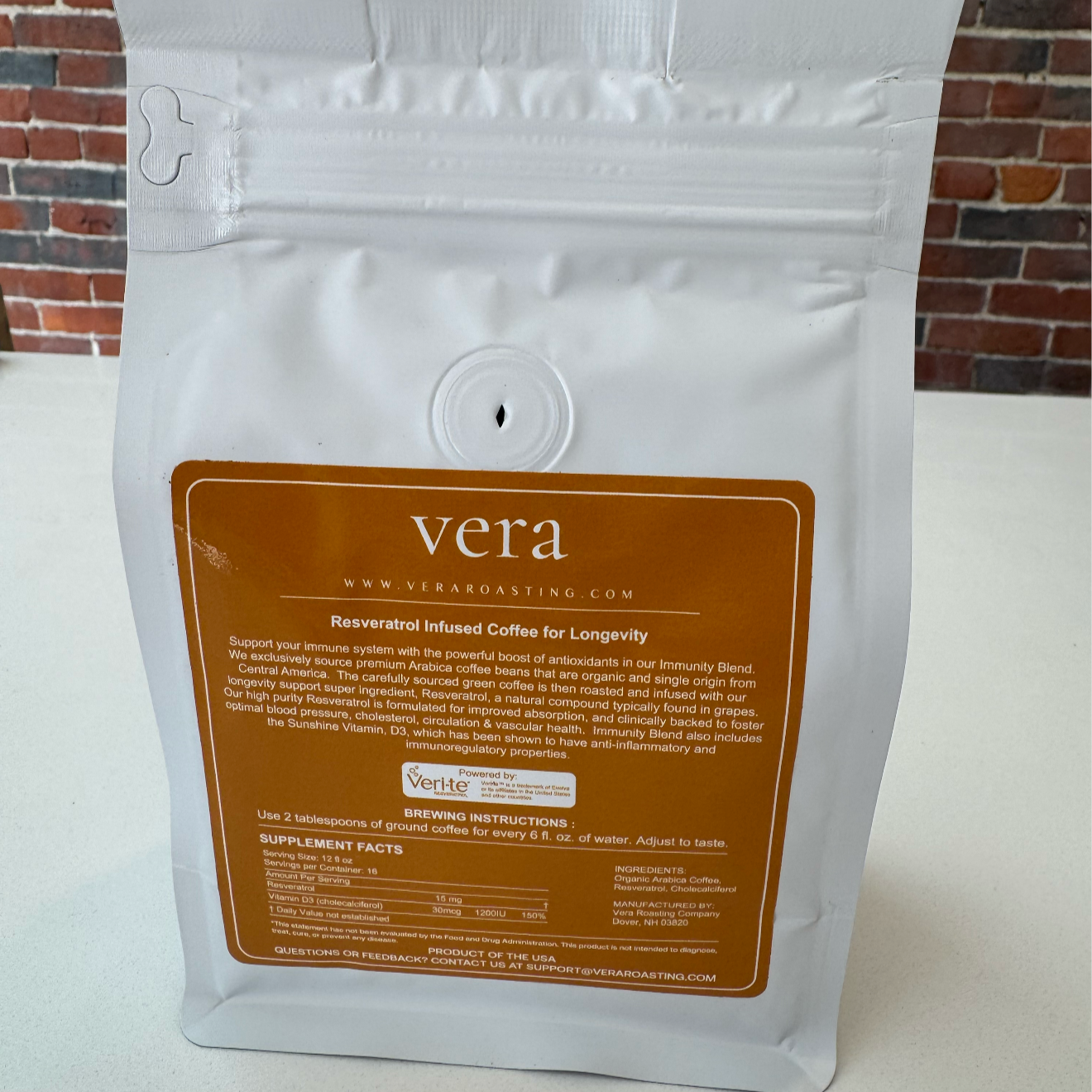 Coffee package with 'Vera' branding on a white surface and brick wall background