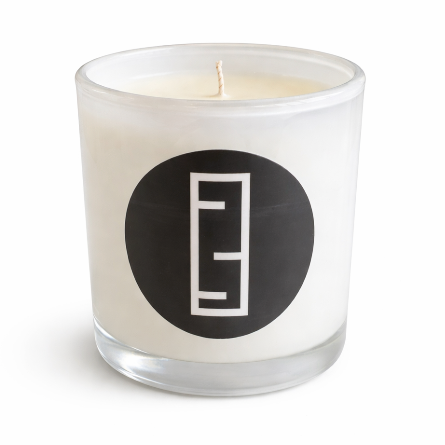 White candle in a glass jar with a black logo on a white background