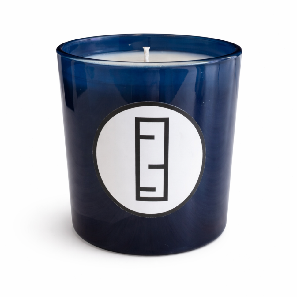 Blue candle jar with a white circular label featuring a black logo on a white background