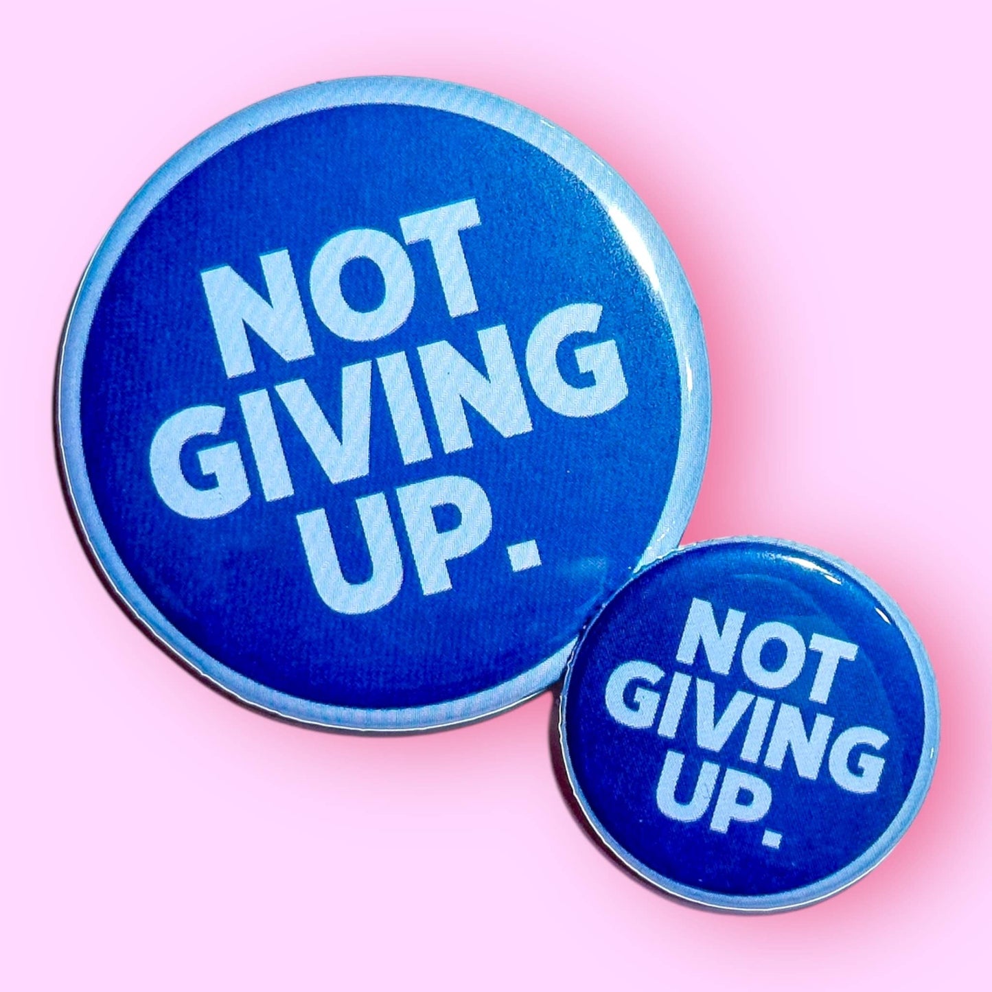 Two blue buttons with 'NOT GIVING UP.' text on a pink background