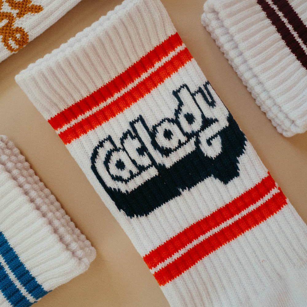 White sock with 'Cat Lady' text and red stripes on a beige surface