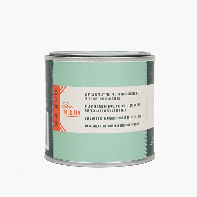 Back label of a candle tin with text and branding on a white background