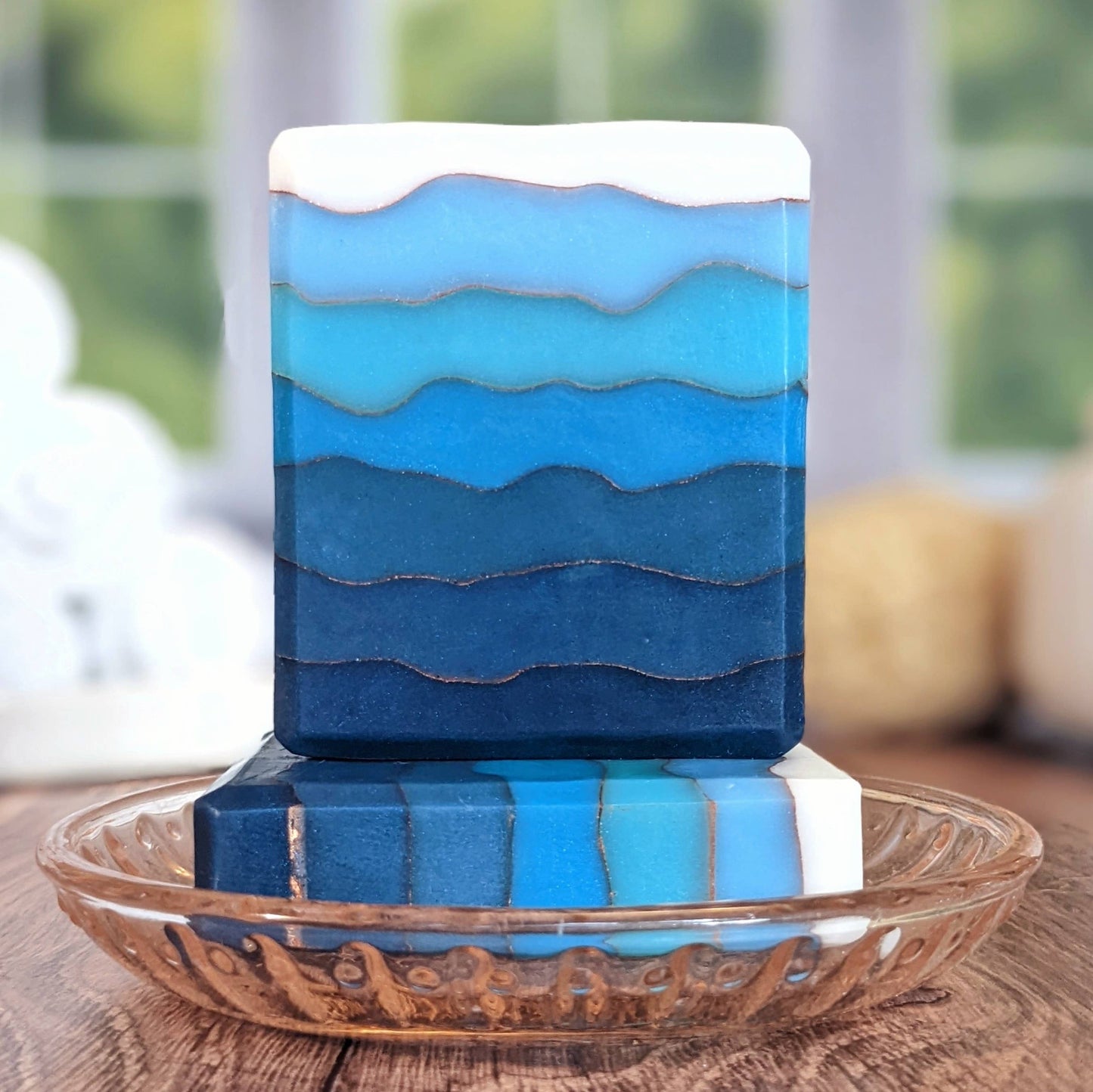 Blue layered soap bar on a glass plate with a blurred background
