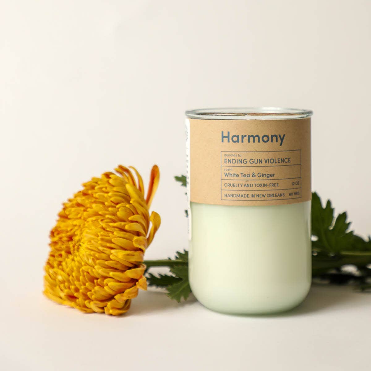 Candle with 'Harmony' label and yellow flower on a light background