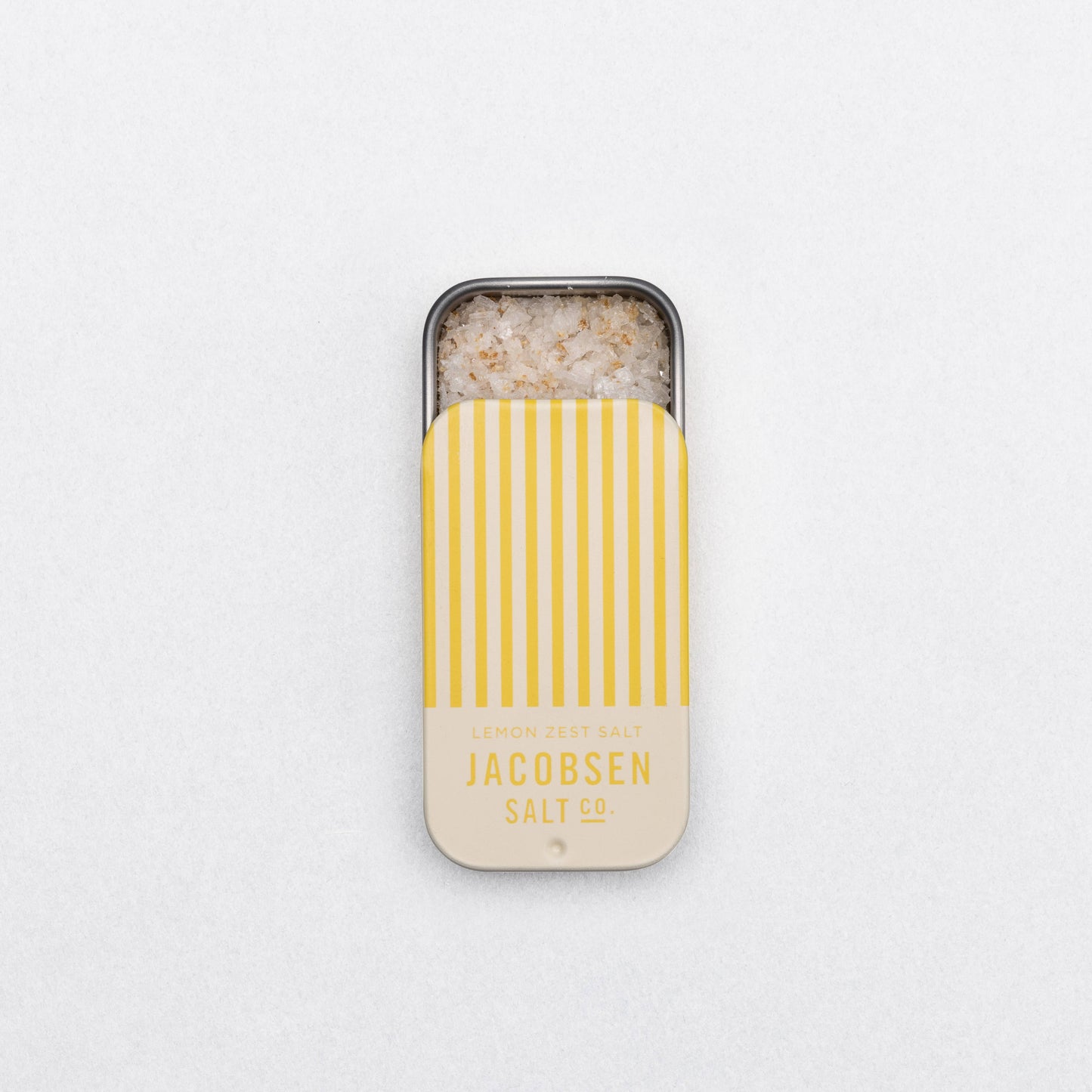 Small container of salt with yellow striped lid on a white background