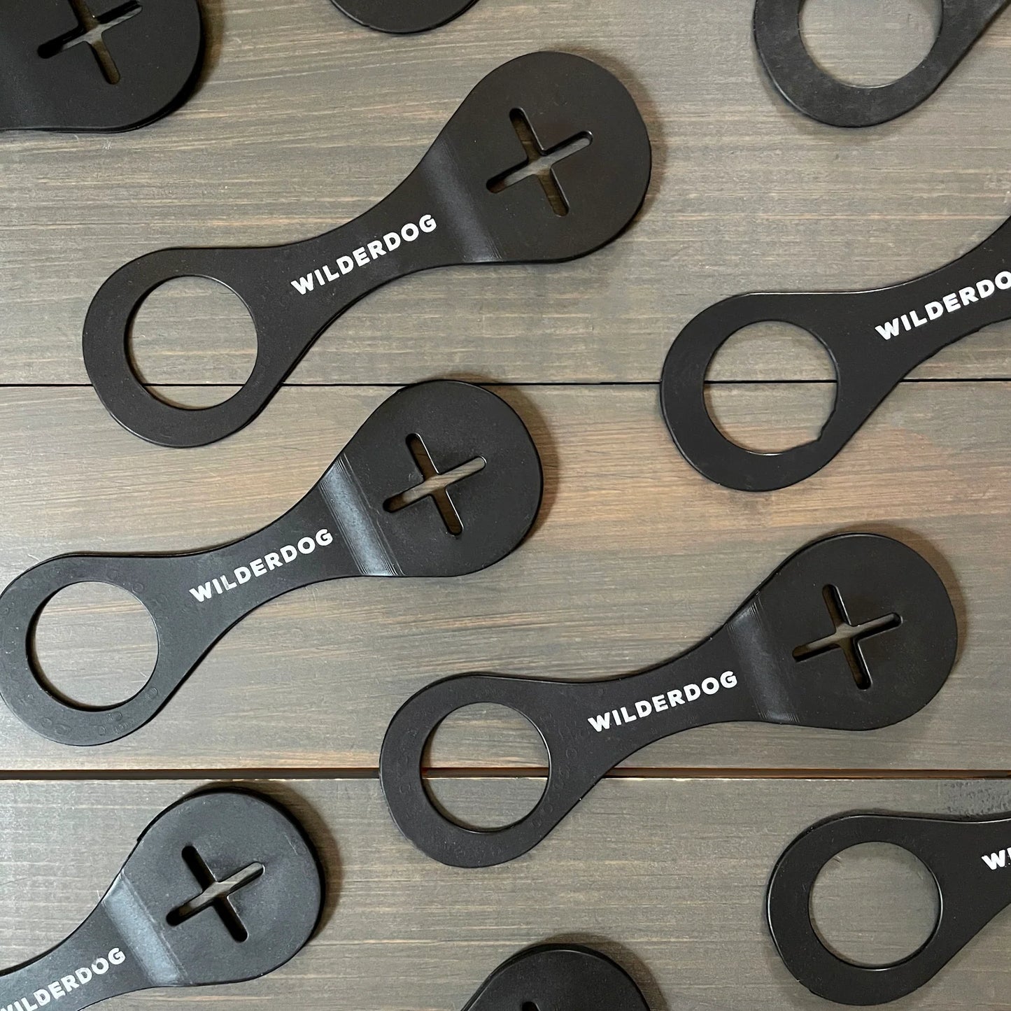 Black metal dog training tools with 'Wilderdog' branding on a wooden surface