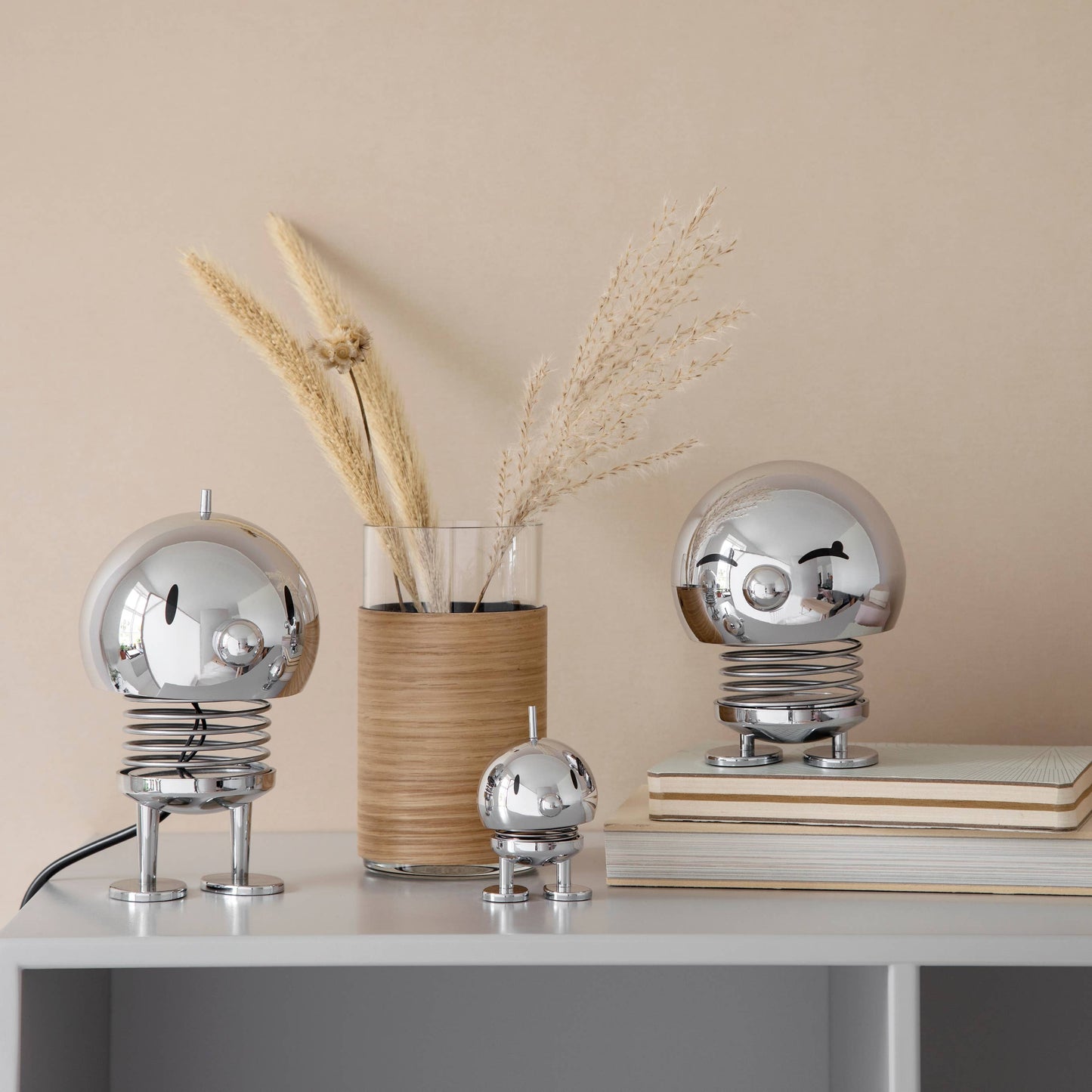 Decorative items including a vase with dried plants and two metallic sculptures on a surface.