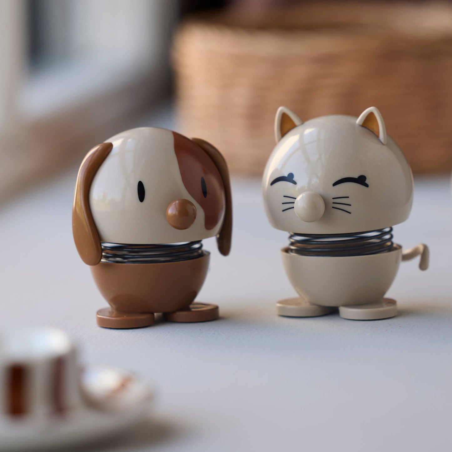 Two small animal figurines on a surface with a window in the background