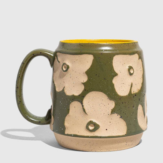 Green ceramic mug with beige floral patterns on a light gray background