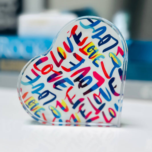 Heart-shaped object with colorful 'I love you' text on a blurred background