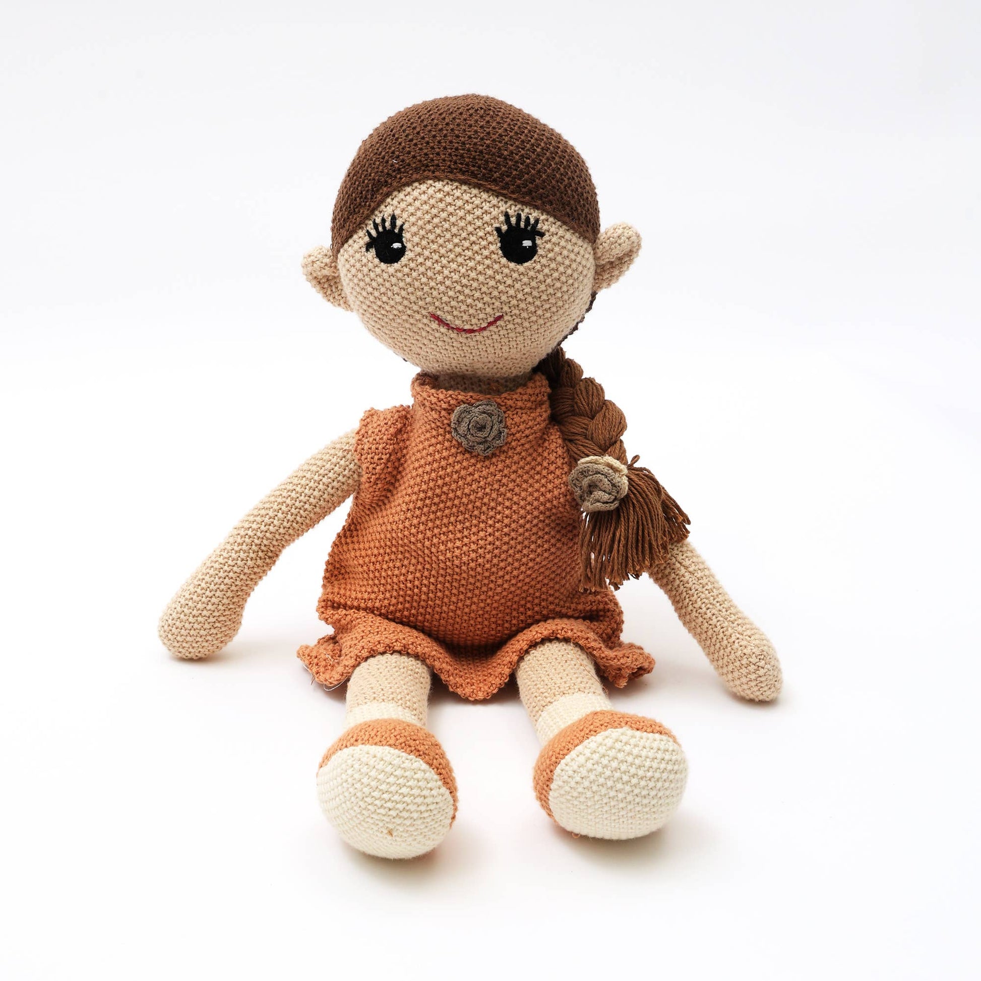 Knitted doll with brown hair and dress on a white background