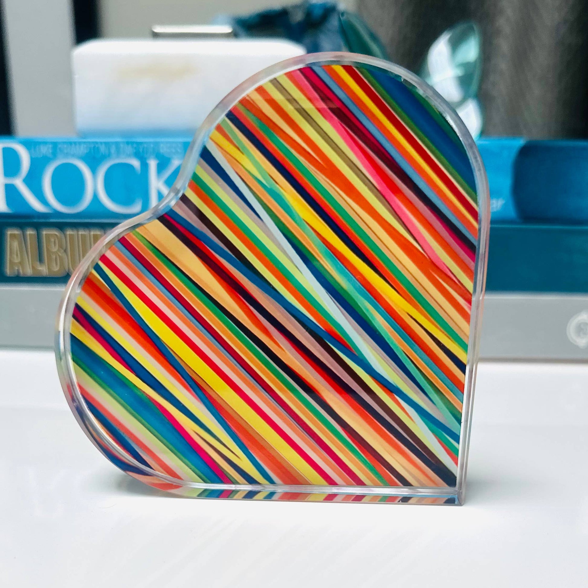 Heart-shaped object with rainbow striped pattern on a white surface