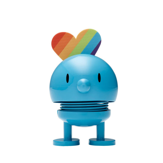 Blue cartoon-like character with a rainbow heart on a white background