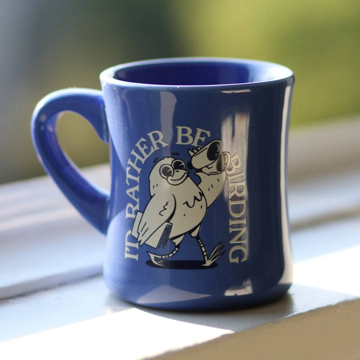Blue mug with a bird design and text on a wooden surface