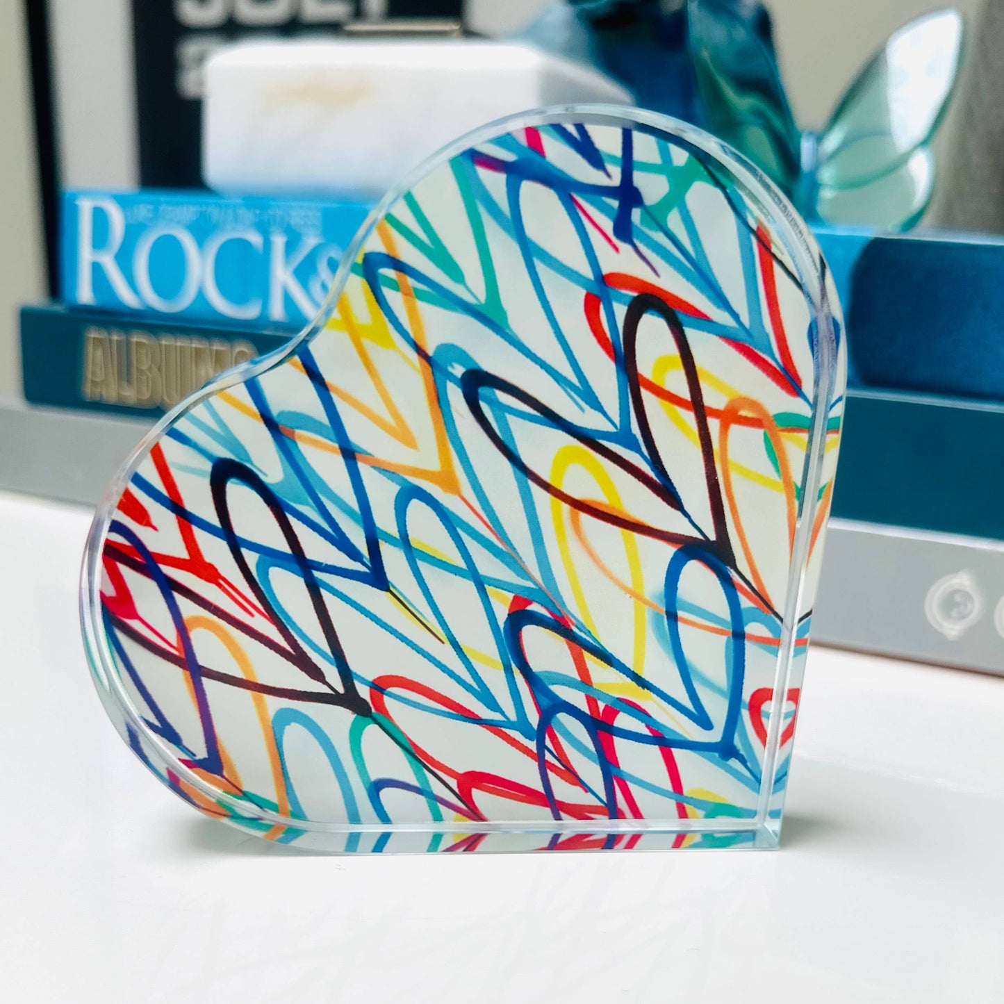 Colorful abstract design on a clear plastic object with books in the background