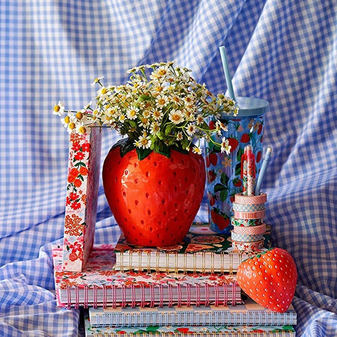 Decorative setup with strawberry-themed items on a blue checkered fabric background