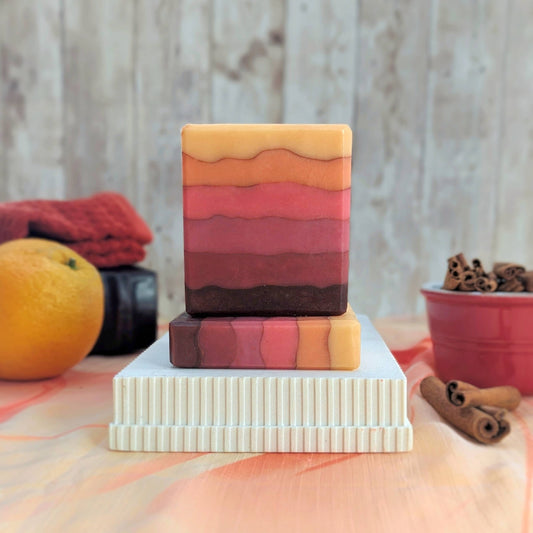 Stack of colorful soap bars on a white stand with a wooden background