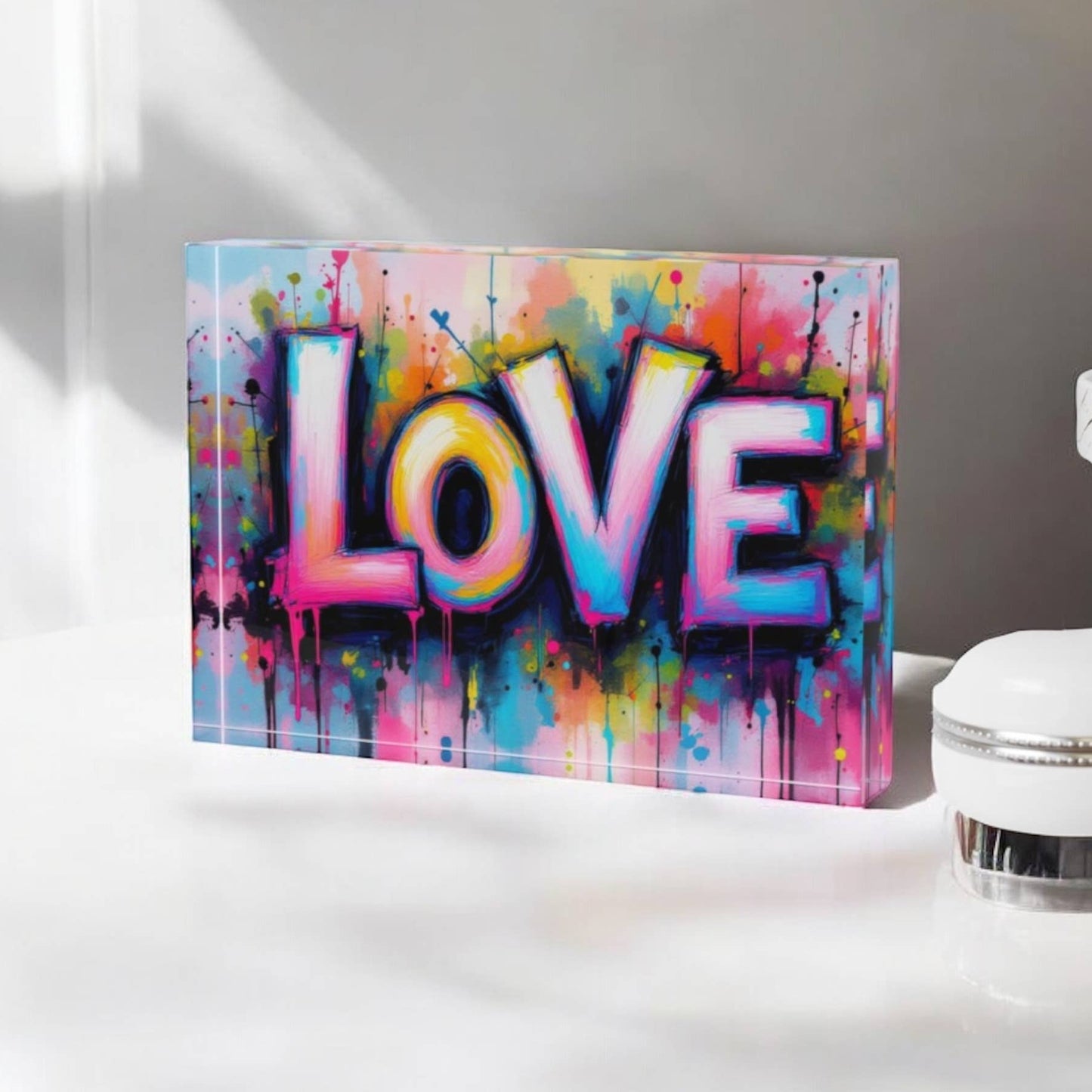 Colorful 'LOVE' artwork on a white surface with a white lamp in the background