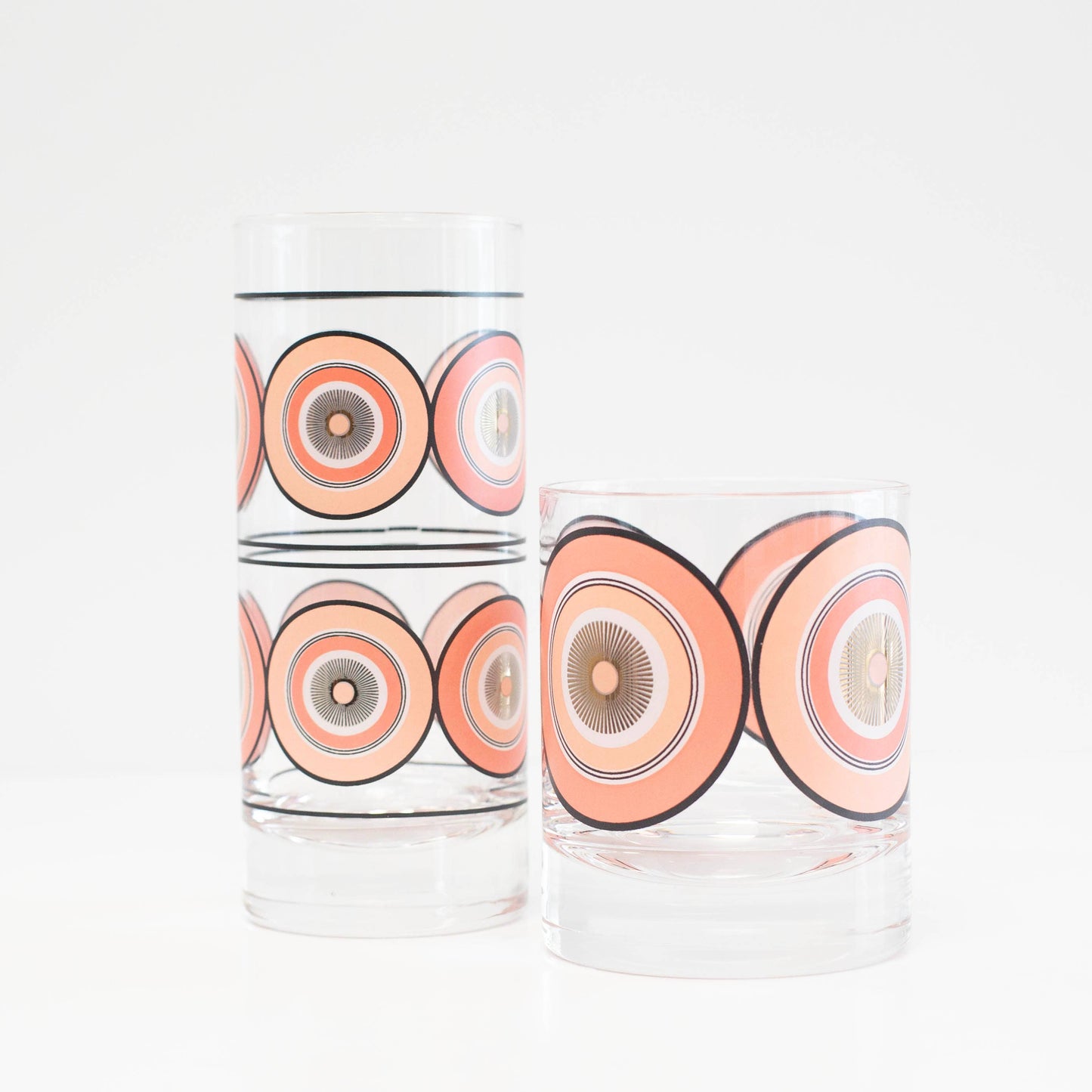 Two cylindrical glass containers with pink circular patterns on a white background