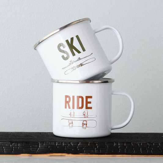 Two white mugs with 'Ski' and 'Ride' text on a wooden surface with a gray background