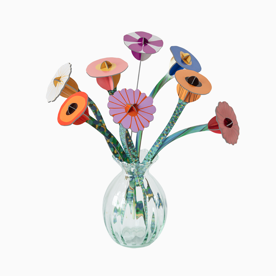 Clear glass vase with colorful ceramic flowers on a white background