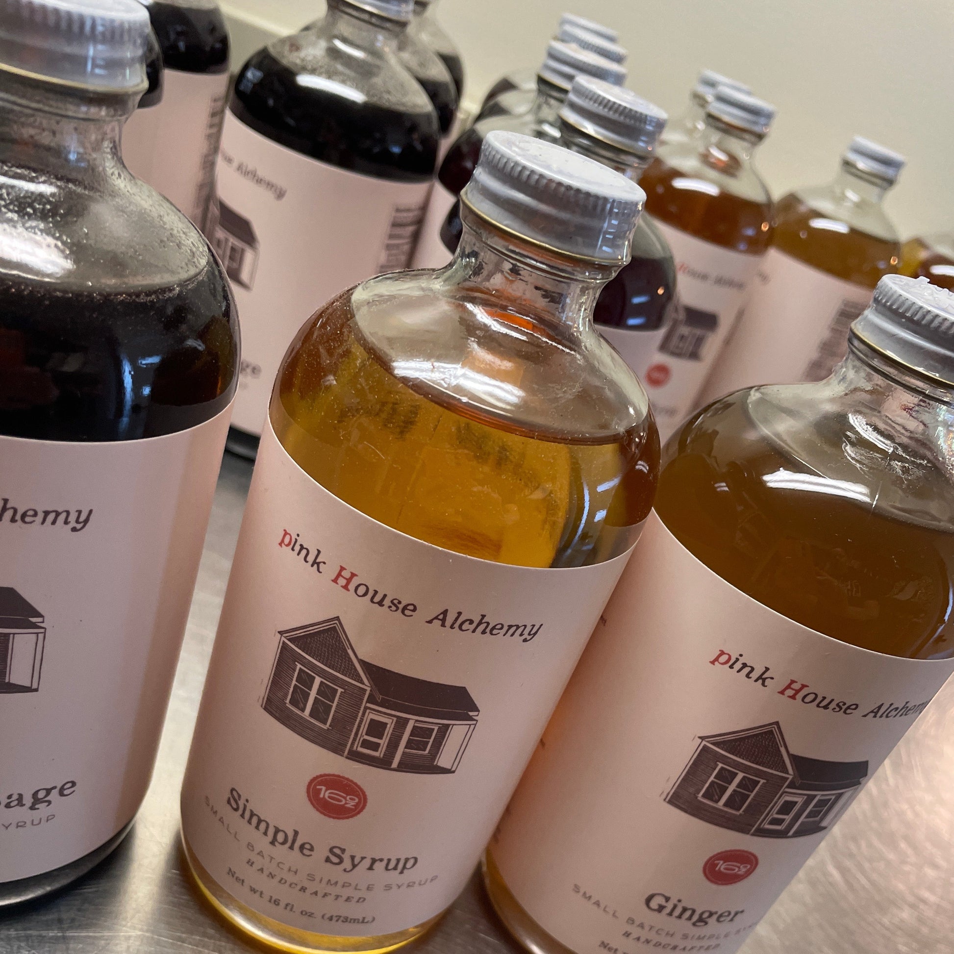 Bottles of Pink House Acheney syrup on a metallic surface