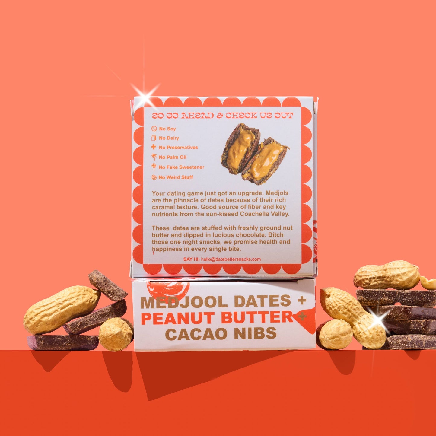 Box of Medjool dates, peanut butter, and cacao nibs on an orange background