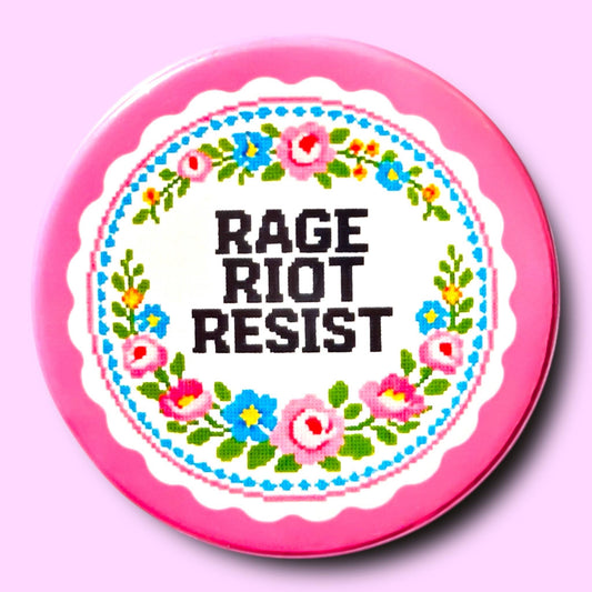 Button badge with 'RAGE RIOT RESIST' text and floral design on a pink background