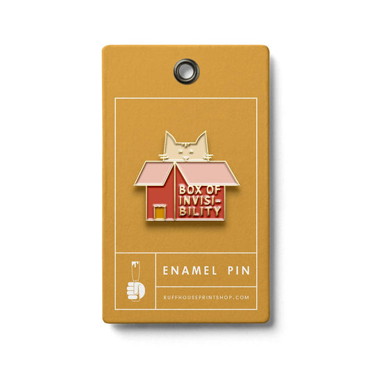 Enamel pin of a cat inside a box labeled 'Box of Invisibility' on a mustard yellow card.