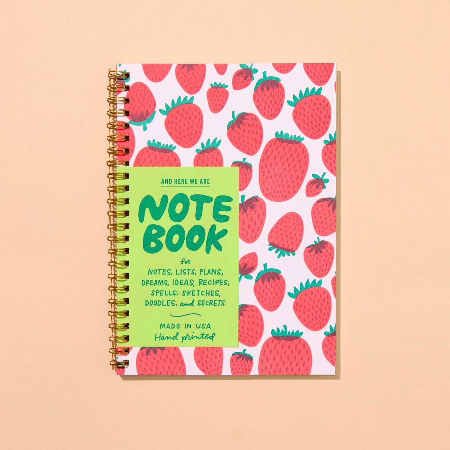 Notebook with strawberry pattern and green label on a beige background