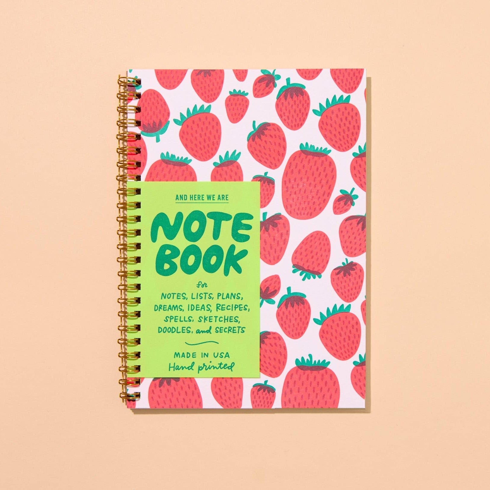 Notebook with strawberry pattern and green label on a beige background