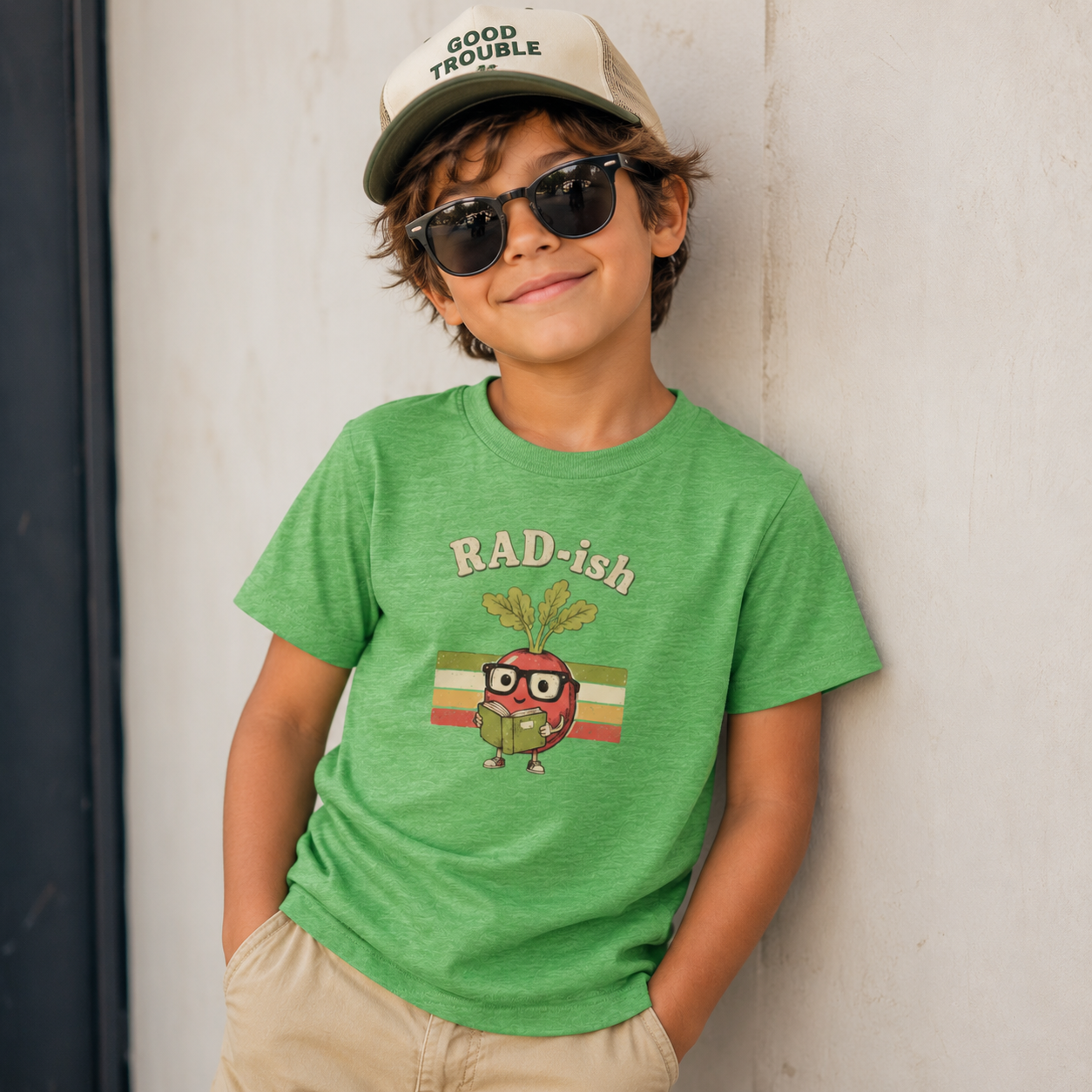 Child wearing a green t-shirt with a radish graphic and sunglasses, standing against a plain background.
