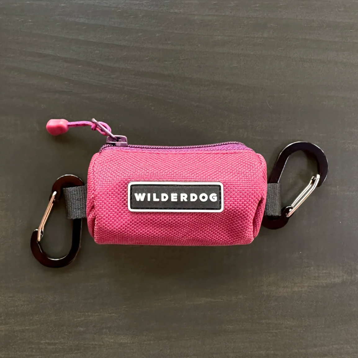 berry pink poop bag holder on a wooden background