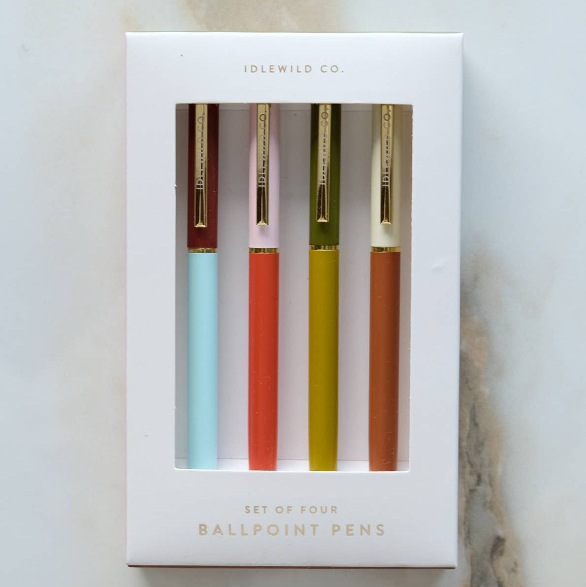 Set of four ballpoint pens in colorful packaging on a marble surface