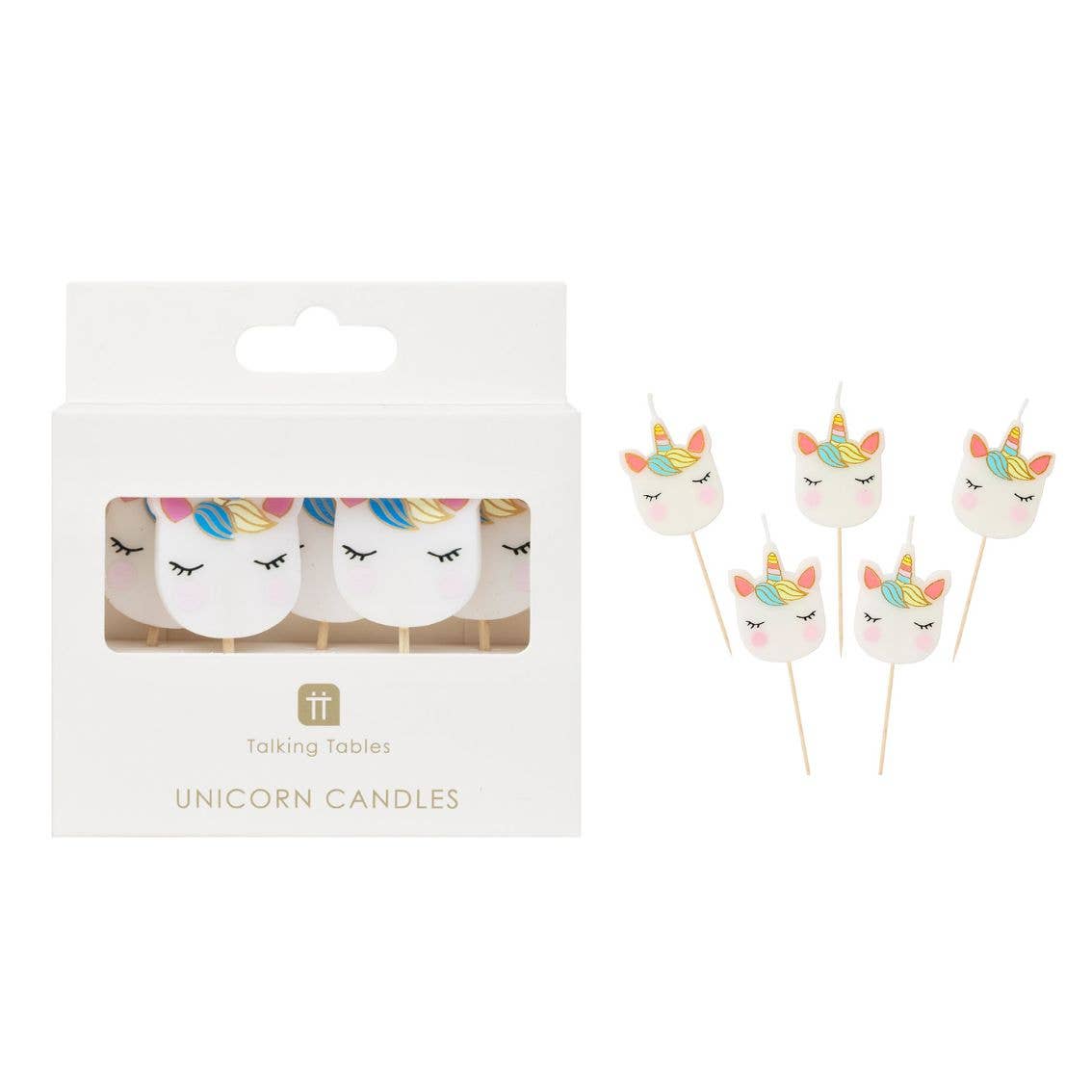 Unicorn-shaped candles with colorful horns in front of their packaging on a white background