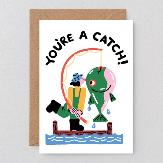 Greeting card with cartoon illustration of a person fishing and text 'YOU'RE A CATCH!' on a white background.