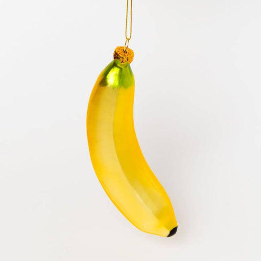 A glossy yellow banana-shaped ornament with a green top and a gold hanging string, shown against a plain white background.