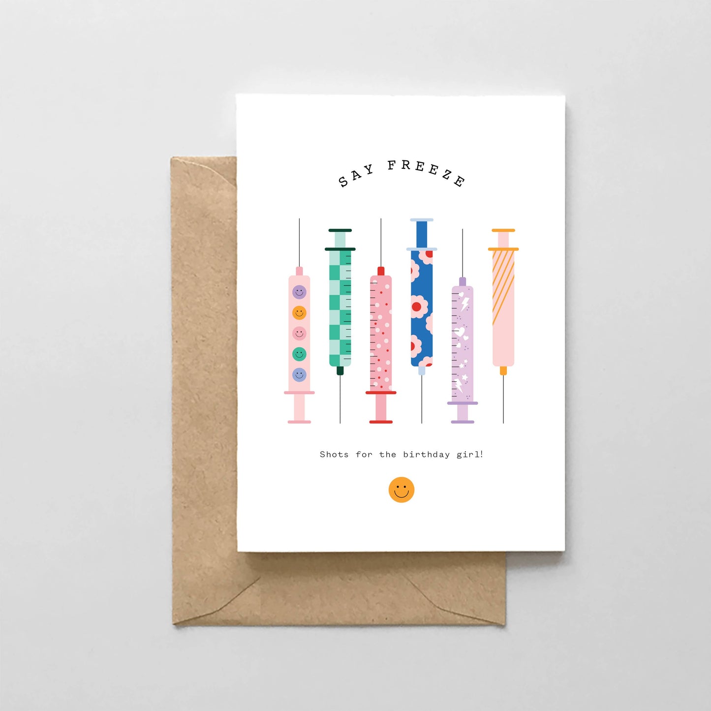 Greeting card with colorful syringe illustrations and a brown envelope on a light gray background