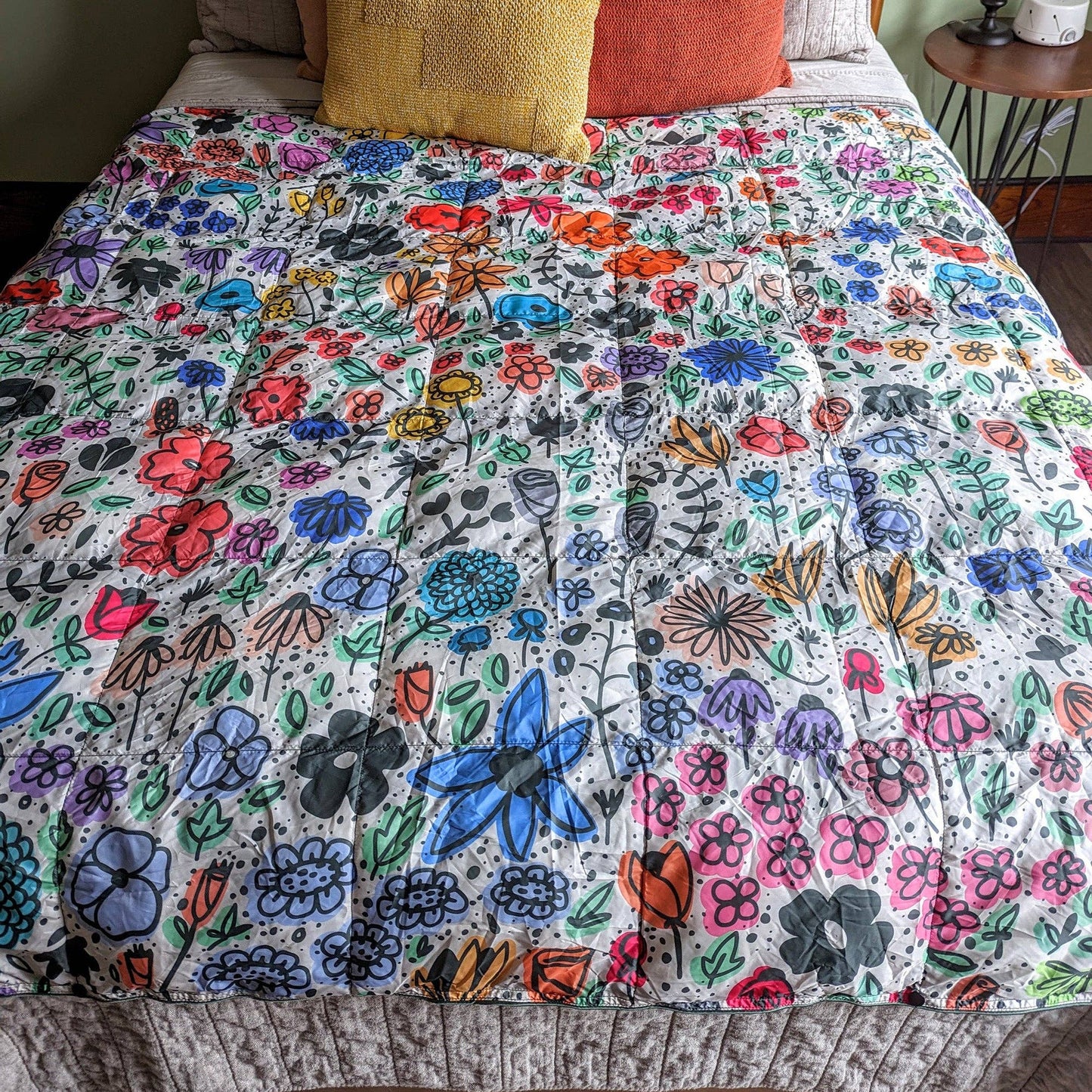 Bed with a colorful floral quilt and patterned pillows.