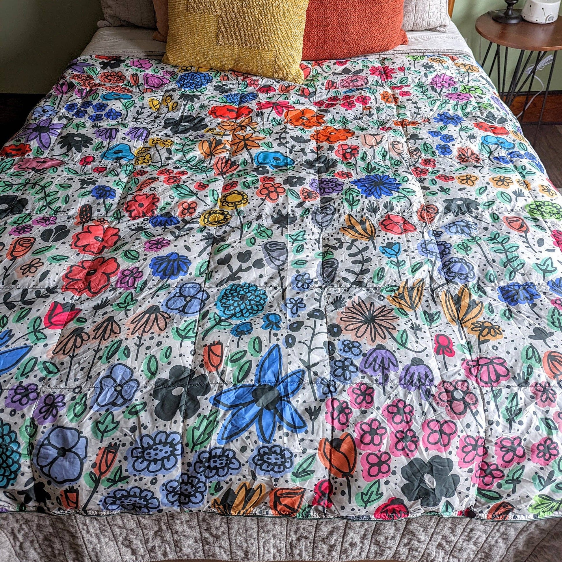 Bed with a colorful floral quilt and patterned pillows.