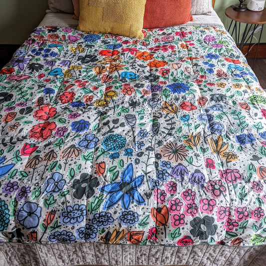 Bed with a colorful floral quilt and patterned pillows.