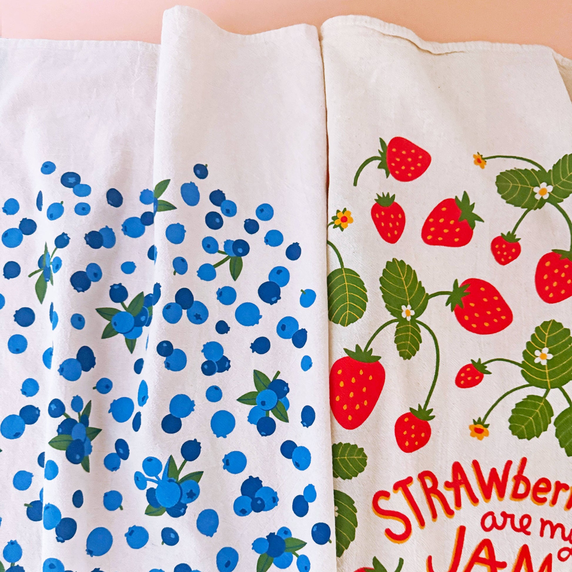 Two fabric swatches with blue berry pattern and strawberry design on a white background.