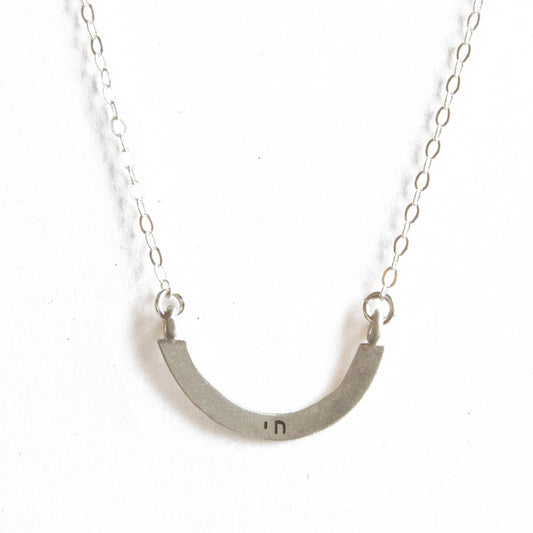 Silver necklace with a curved pendant on a white background
