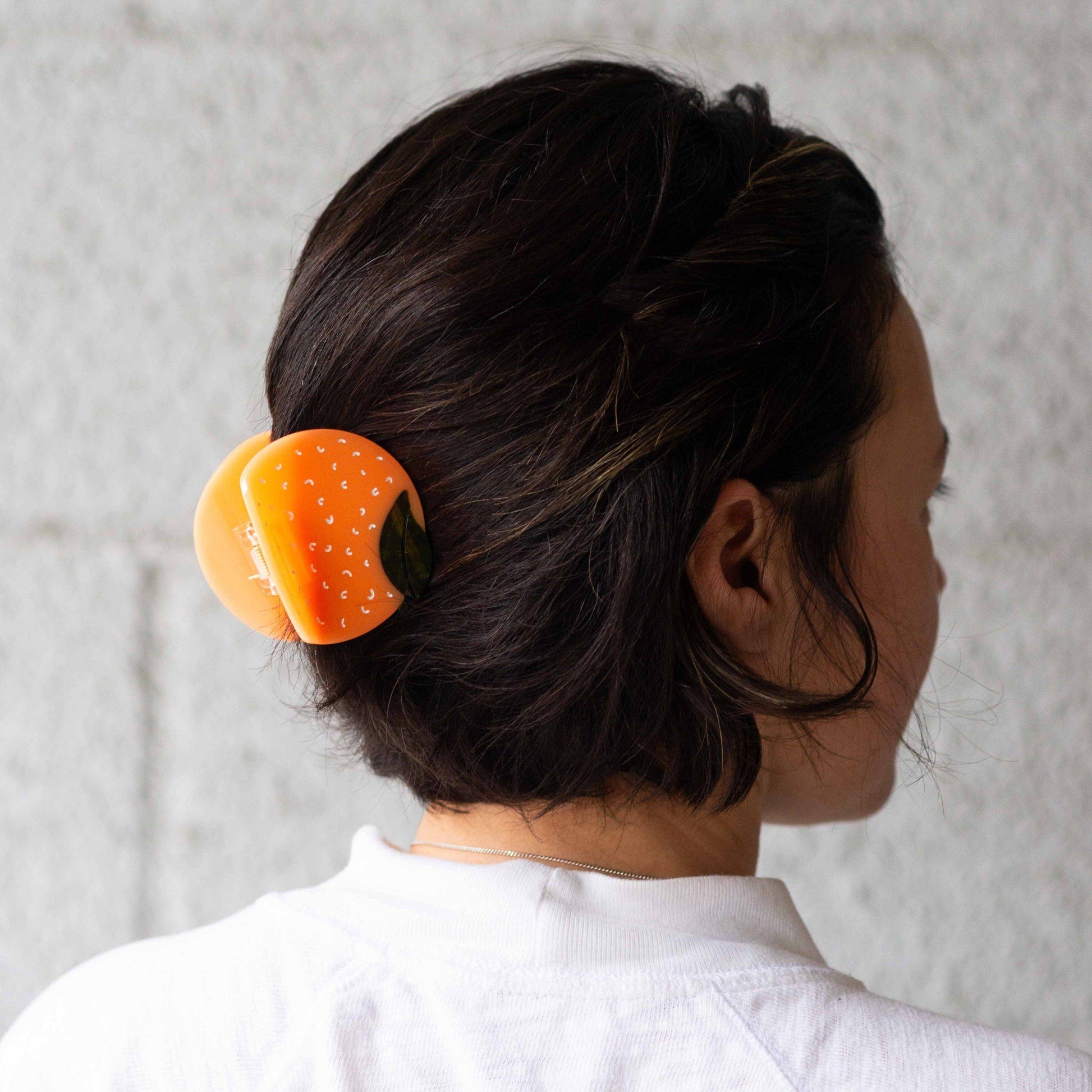 Person with a hair clip in their hair against a neutral background
