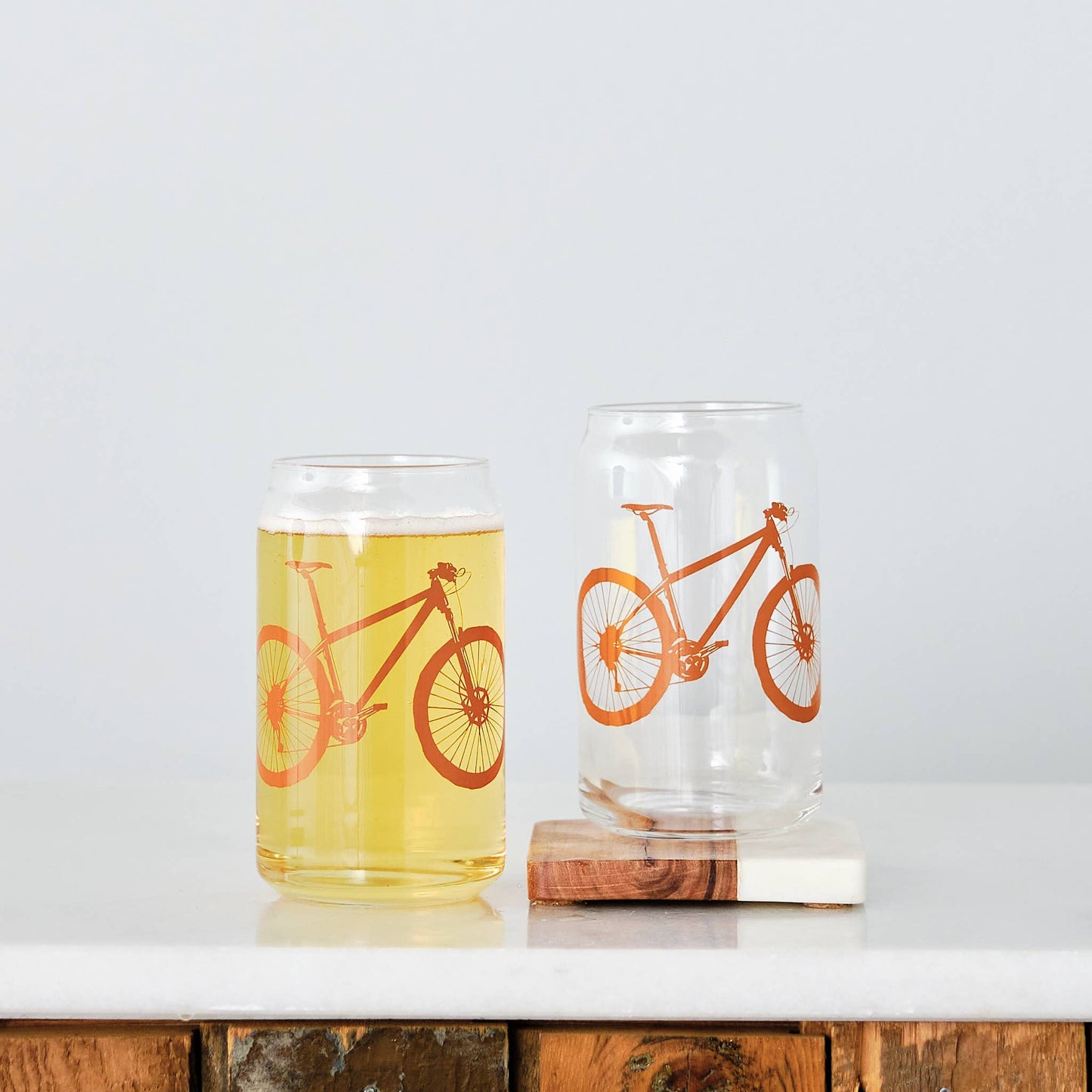 Two glasses with bicycle designs on a white surface.